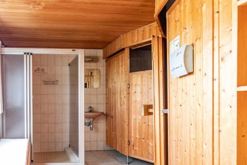 a bathroom with wooden walls and a shower and a sink at Bergzicht in Schwalefeld
