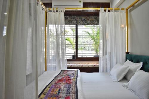 a bedroom with a bed with white curtains and a window at Shanti Villas - Luxury Home Stay Apartment in Jaipur