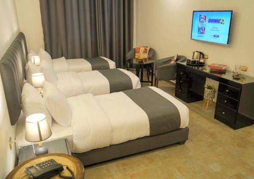 a hotel room with two beds and a television at Torino Hotel Amman in Amman