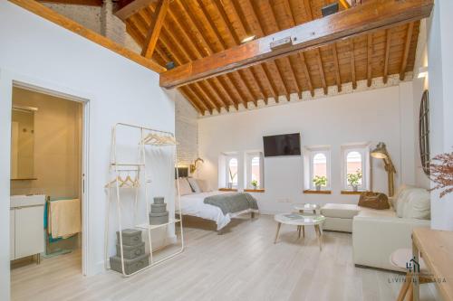 Elle comprend un salon doté de murs blancs et de plafonds en bois. dans l'établissement Living4Malaga Skyline Apartments, à Malaga