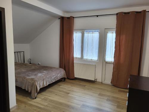 a bedroom with a bed and two windows at Casa Berbece in Moieciu de Jos