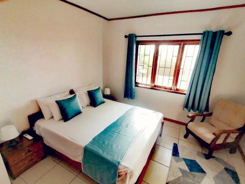 a bedroom with a bed and a chair and a window at Roz A Mer - Beach Apartment in Mahe