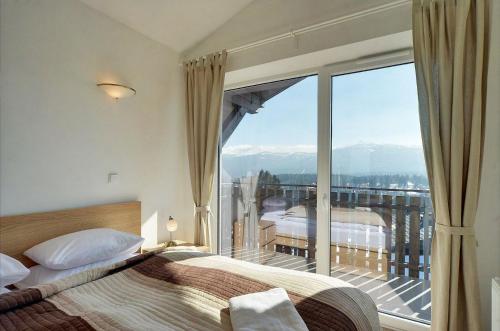 a bedroom with a bed and a balcony with a view at Apart Invest Perła B11 in Szklarska Poręba