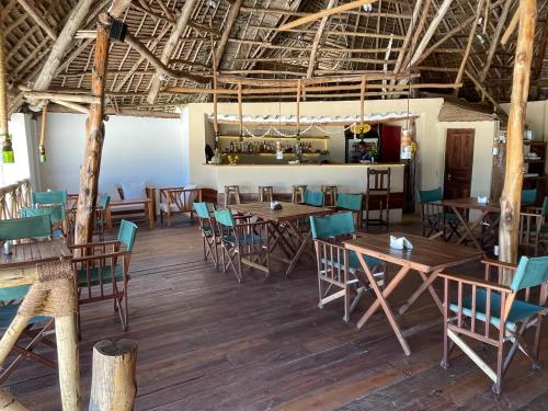 comedor con mesas y sillas de madera en HEBE Bungalows Lodge, en Matemwe