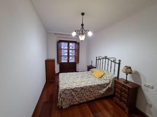 a bedroom with a bed and a lamp and a window at 117A - Elegante apartamento en pleno centro in Gijón