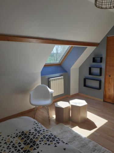 a attic bedroom with a bed and a white chair at chambre chez habitant avec petit déjeuner in Bouloire