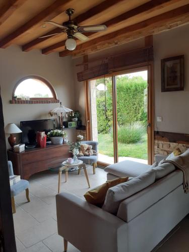 un salon avec un canapé et un ventilateur de plafond dans l'établissement chambre chez habitant avec petit déjeuner, à Bouloire