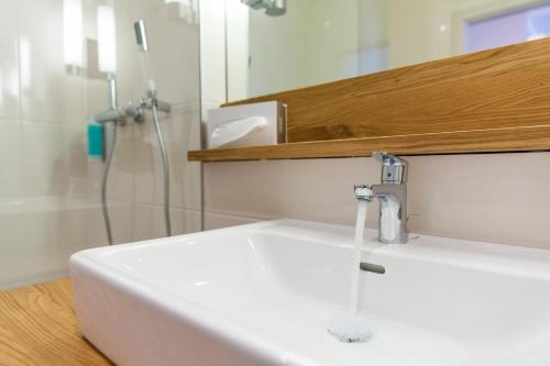 La salle de bains est pourvue d'un lavabo blanc et d'une douche. dans l'établissement feel good Resort, à Krumpendorf am Wörthersee