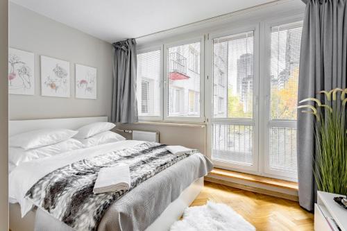 sypialnia z łóżkiem i dużym oknem w obiekcie Hala Mirowska Apartments w Warszawie