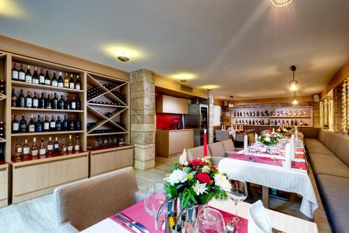 a restaurant with tables and chairs and wine bottles at Hotel & Relax Zone Cattleya in Krushuna