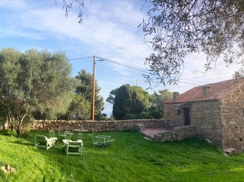 einen Garten mit Tischen und Stühlen und ein Steingebäude in der Unterkunft Domaine de la coletta Maison traditionnelle in Coti-Chiavari