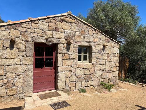 - un petit bâtiment en pierre avec une porte rouge dans l'établissement Domaine de la Coletta. Bergerie. Plage privative, à Coti-Chiavari