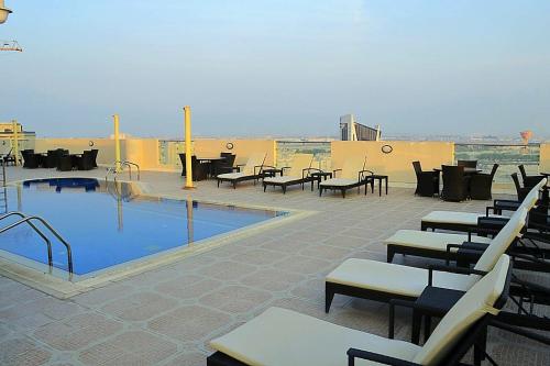um pátio com uma piscina, mesas e cadeiras em Wonder Palace Hotel Qatar em Doha