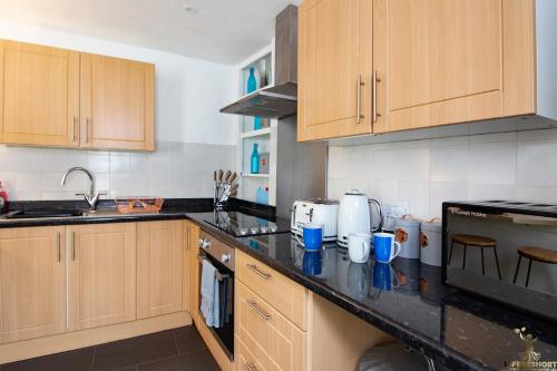 a kitchen with wooden cabinets and a black counter top at Modern Quirky Exeter City Cottage 2 min walk - shops in Exeter