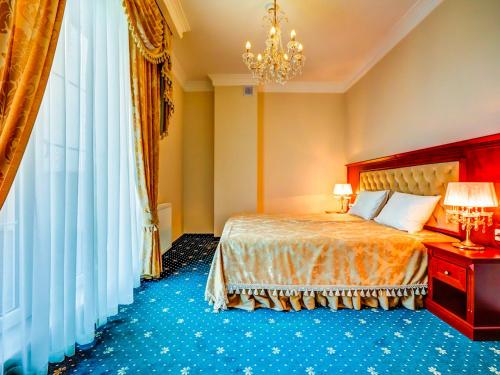 ein Hotelzimmer mit einem Bett und einem Kronleuchter in der Unterkunft Parisel Palace Centrum Konferencyjno-Wypoczynkowe Klimki pod Łukowem in Łuków