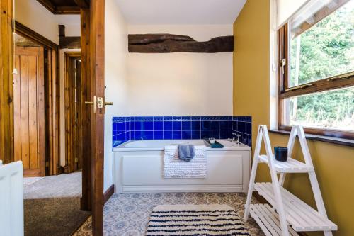 a bathroom with a tub and blue tiles at Finest Retreats - Idris Barn Helm y Llwyn Barn in Dolgellau