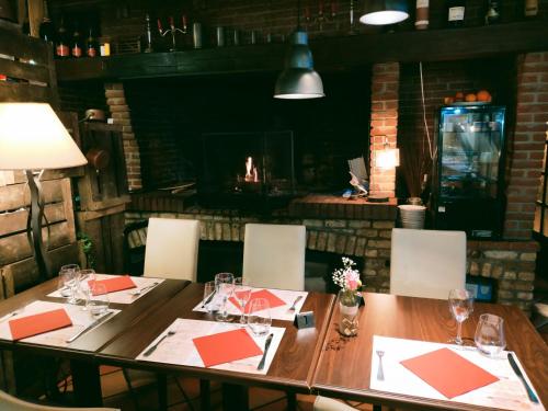 a wooden table in a restaurant with a fireplace at Hôtel Restaurant l’Éolienne in Rouxmesnil-Bouteilles