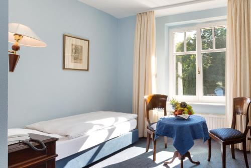 a bedroom with a bed and a table and a window at Schlosshotel Ralswiek in Ralswiek