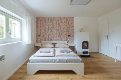 een witte slaapkamer met een bed en een open haard bij Old Nest Mogyoród in Mogyoród