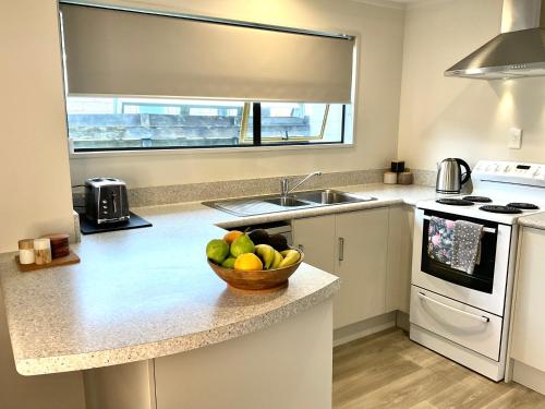 a kitchen with a bowl of fruit on a counter at Aintree On The Park in Mount Maunganui