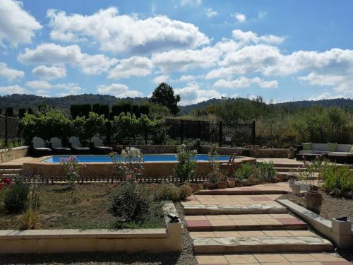 een achtertuin met een zwembad en stoelen en planten bij Casa De Madera, A home from home. in Teresa de Cofrentes