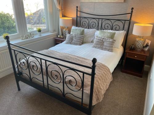 a black bed with pillows in a bedroom with windows at Beechwood Ensuite Guest House in Ayr