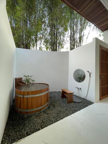 La salle de bains est pourvue d'une baignoire en bois dans un mur blanc. dans l'établissement Le Sen Boutique Hotel, à Luang Prabang