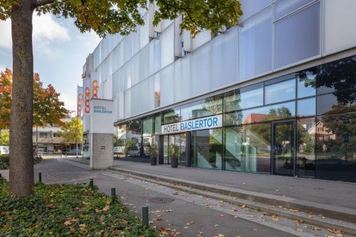 a large glass building with a sign that reads msg exterior at Hotel Baslertor in Muttenz