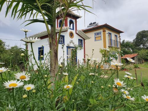 a house with a tree and flowers in front of it at Recanto Bom Despacho in Tiradentes