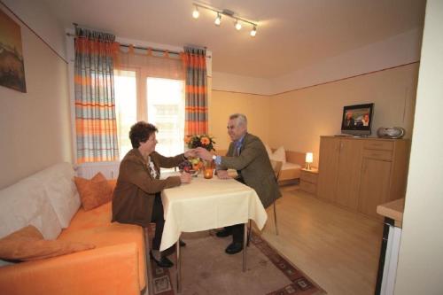 two people sitting at a table in a living room at Appartement Haus Salzburg in Bad Füssing