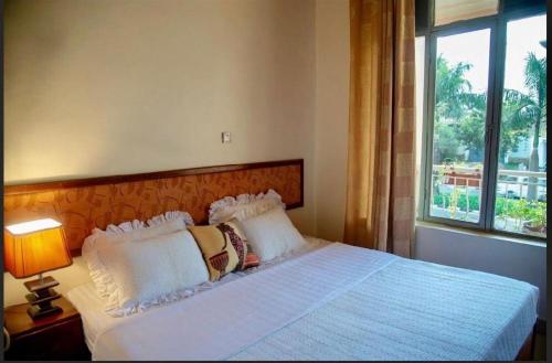 a bedroom with a white bed with a window at Hotel Greenwich in Kigali
