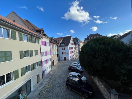 a group of cars parked in a street with buildings at Appartement atypique à la Cour-aux-Moines - plein centre historique in Porrentruy
