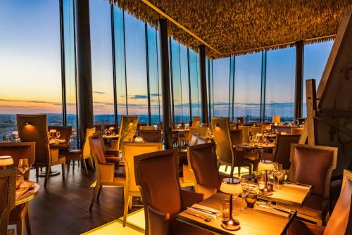 a restaurant with tables and chairs and windows at Too Hotel & Spa Paris - MGallery Collection in Paris