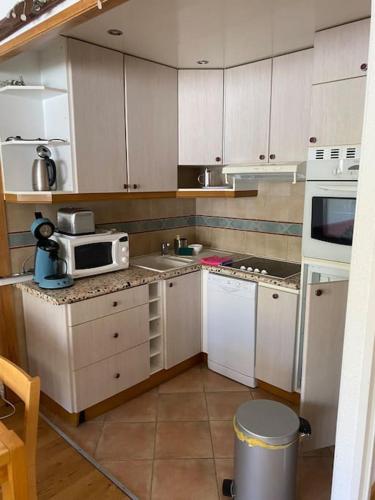 une cuisine avec des armoires blanches et un micro-ondes dans l'établissement Cosy F2 Val Claret 6 couchages avec jolie vue sud ouest, à Tignes