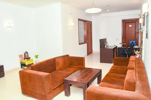 古爾岡的住宿－FabHotel Premium，客厅配有2张棕色沙发和1张桌子