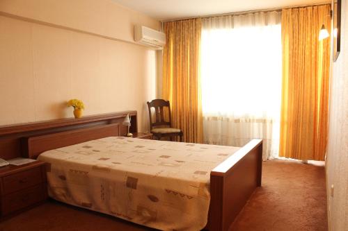 a bedroom with a bed and a window and a chair at Hotel Turist in Chişinău