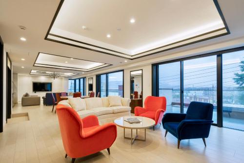a living room with red chairs and a couch at Grand Phenix Hakuba by Jade Villa in Hakuba