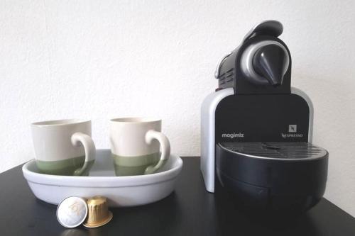 a coffee maker and two cups on a table at Huningue des trois frontières in Huningue