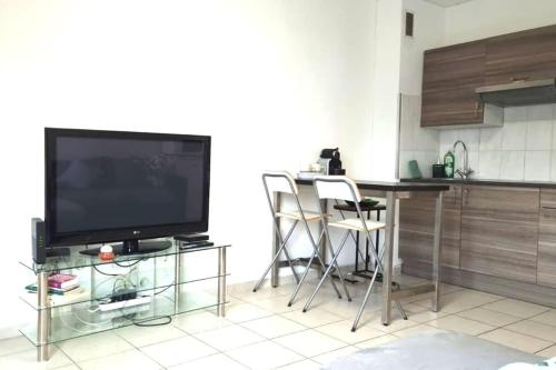a kitchen with a television and a table with chairs at Huningue des trois frontières in Huningue