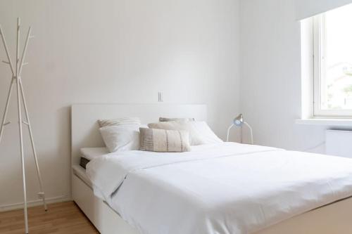 Dormitorio blanco con cama con sábanas y almohadas blancas en 1br apartment with patio in Lauttasaari, en Helsinki
