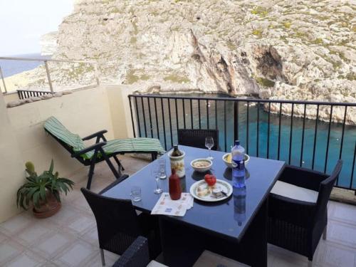 una mesa y sillas en un balcón con vistas al océano en Seafront Penthouse with Terrace in Xlendi, Gozo, en Xlendi