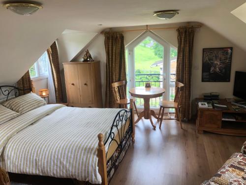 a bedroom with a bed and a table and a window at Lake view Romantic retreat in Aberystwyth