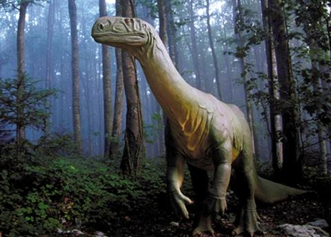 a statue of a dinosaur standing in a forest at Appartement atypique à la Cour-aux-Moines - plein centre historique in Porrentruy