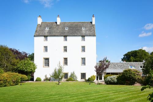 a large white house with a green lawn at Macdonald Houstoun House in Livingston
