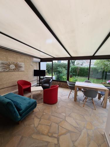 een woonkamer met een bank en een tafel en stoelen bij Studio entièrement équipé avec véranda commune in Neuilly-sur-Marne