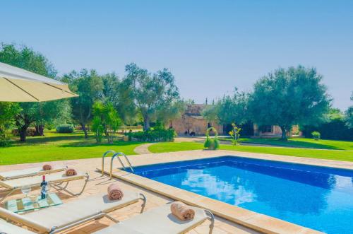 a swimming pool with two chairs and an umbrella at S'Era Nova in Algaida