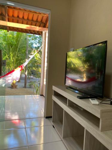 ein Wohnzimmer mit einem Flachbild-TV neben einem Fenster in der Unterkunft Chalés toca do guaxinim in Itarema