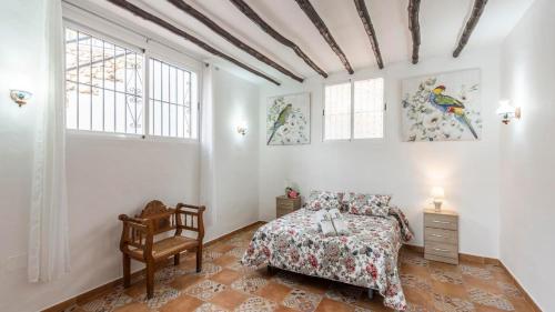 una camera con letto, sedia e finestre di Villa Santo Cristo Frigiliana by Ruralidays a Frigiliana
