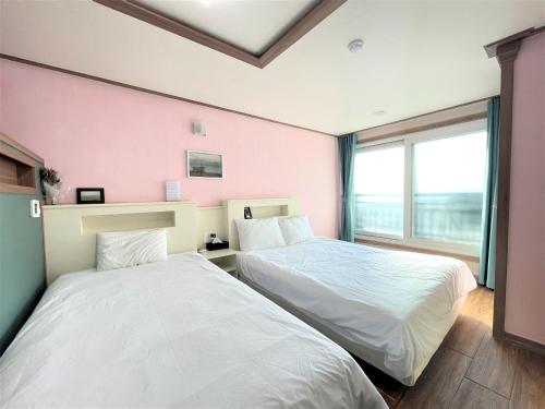two beds in a room with pink walls at HY Choi Hostel in Seogwipo