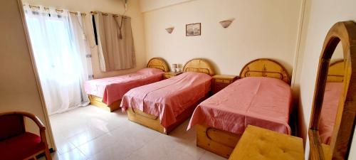 a room with three beds and a window at Senmut Luxory Rooms in Luxor